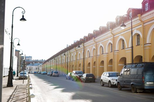 A bright urban street lined with historic, arched buildings and parked cars, showcasing a classic architectural style.