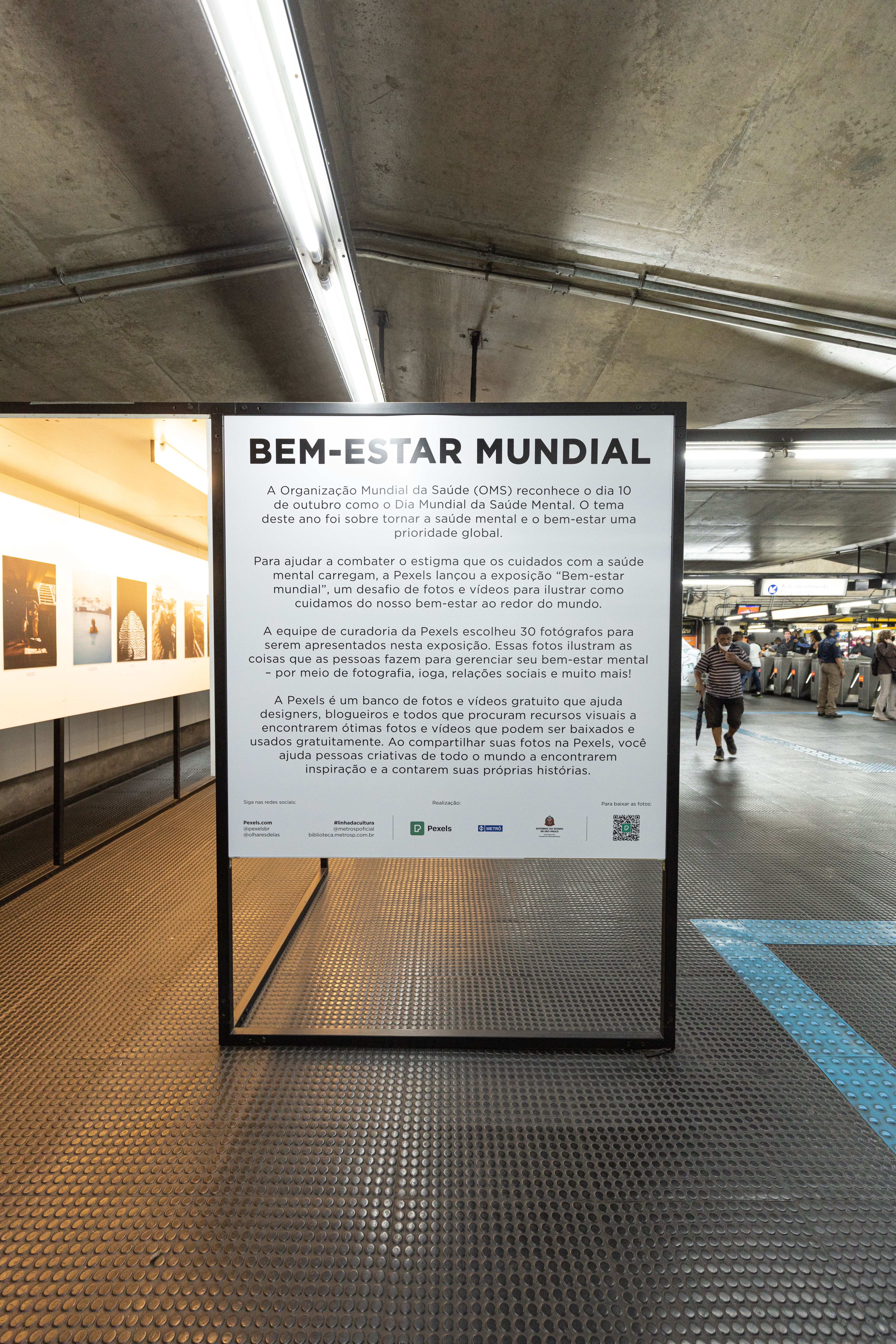 A public transport station with a prominent information board and people walking.