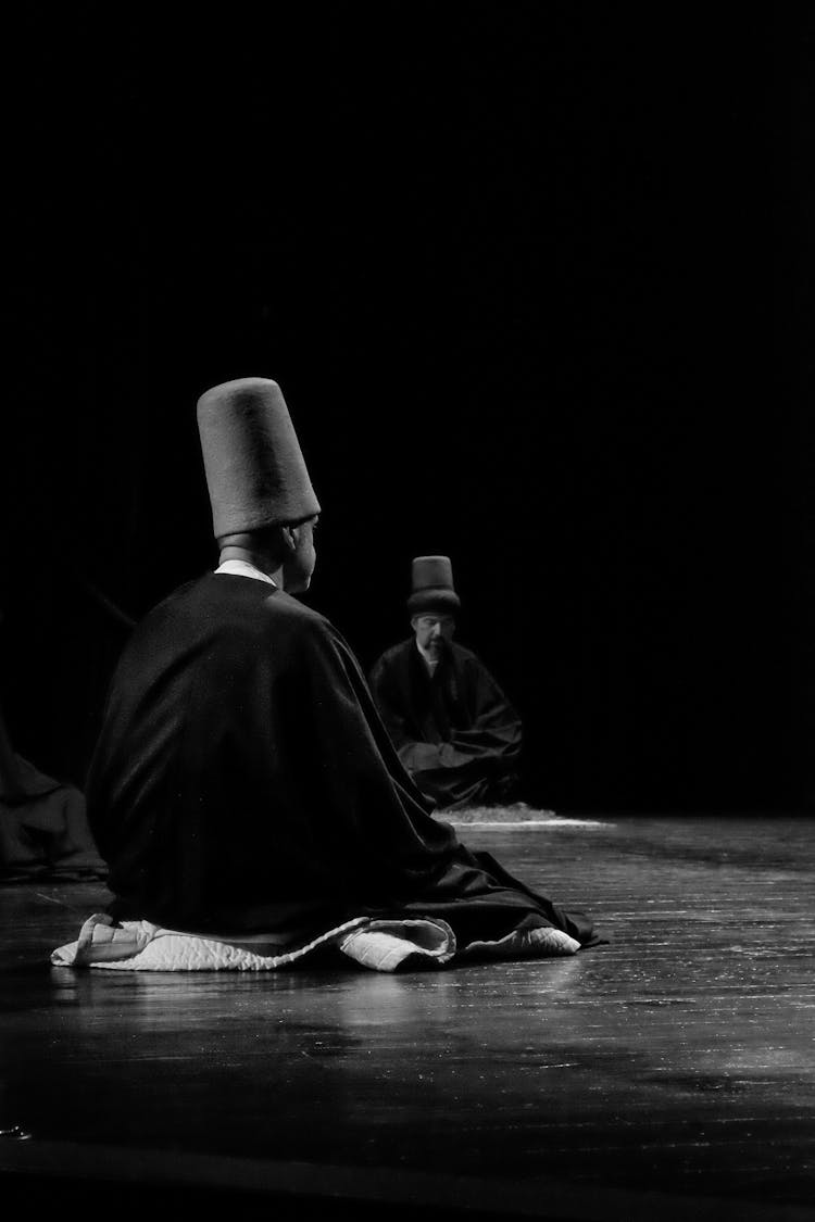 Black And White Shot Of Men Sitting On A Stage