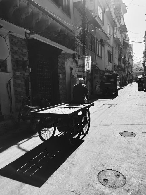 Free A black and white photo of a person pulling a cart on a city street during the day. Stock Photo