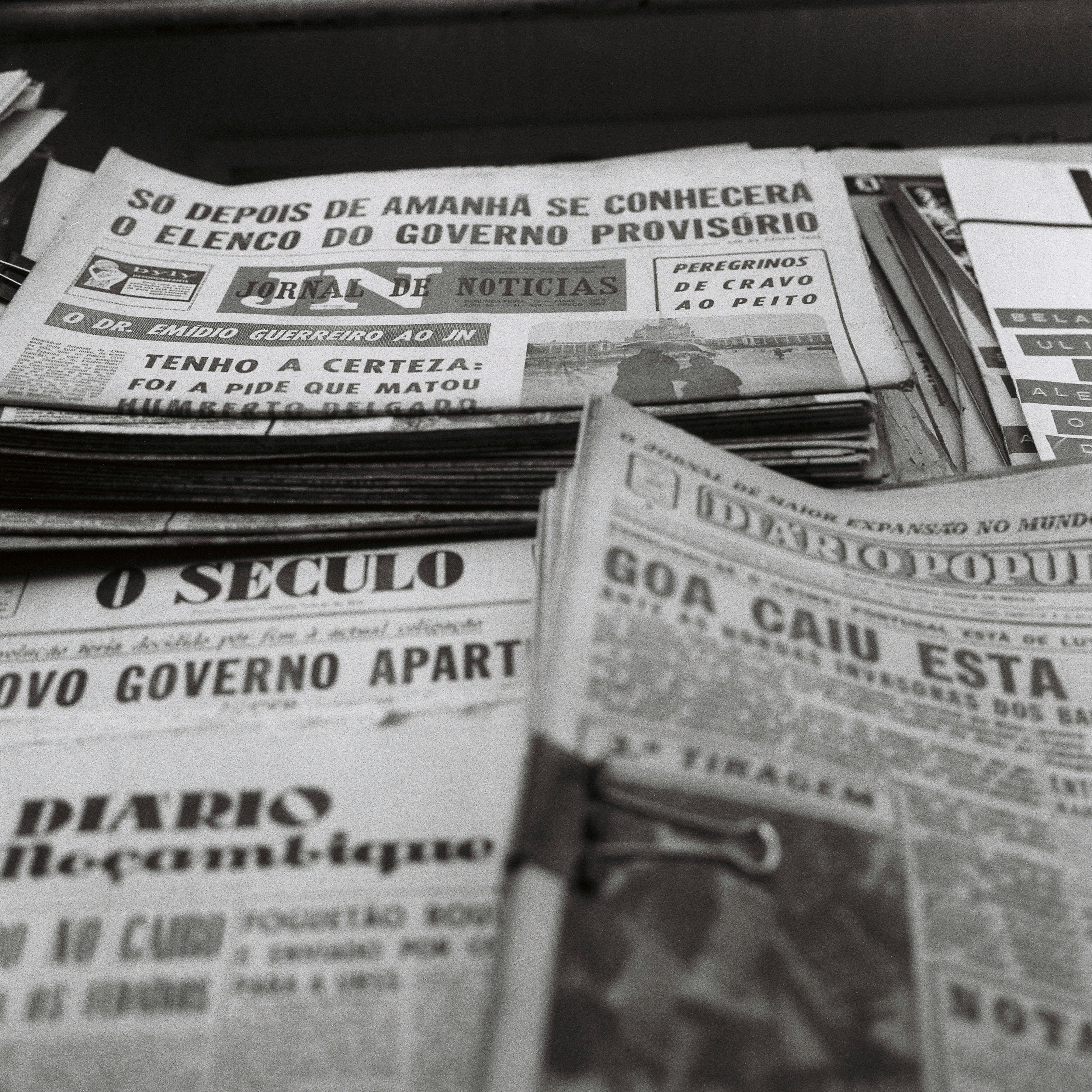 Newspapers are piled up on a table