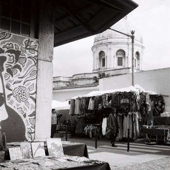 Monochrome view of a lively street market in Lisbon, showcasing clothing stalls and urban architecture.