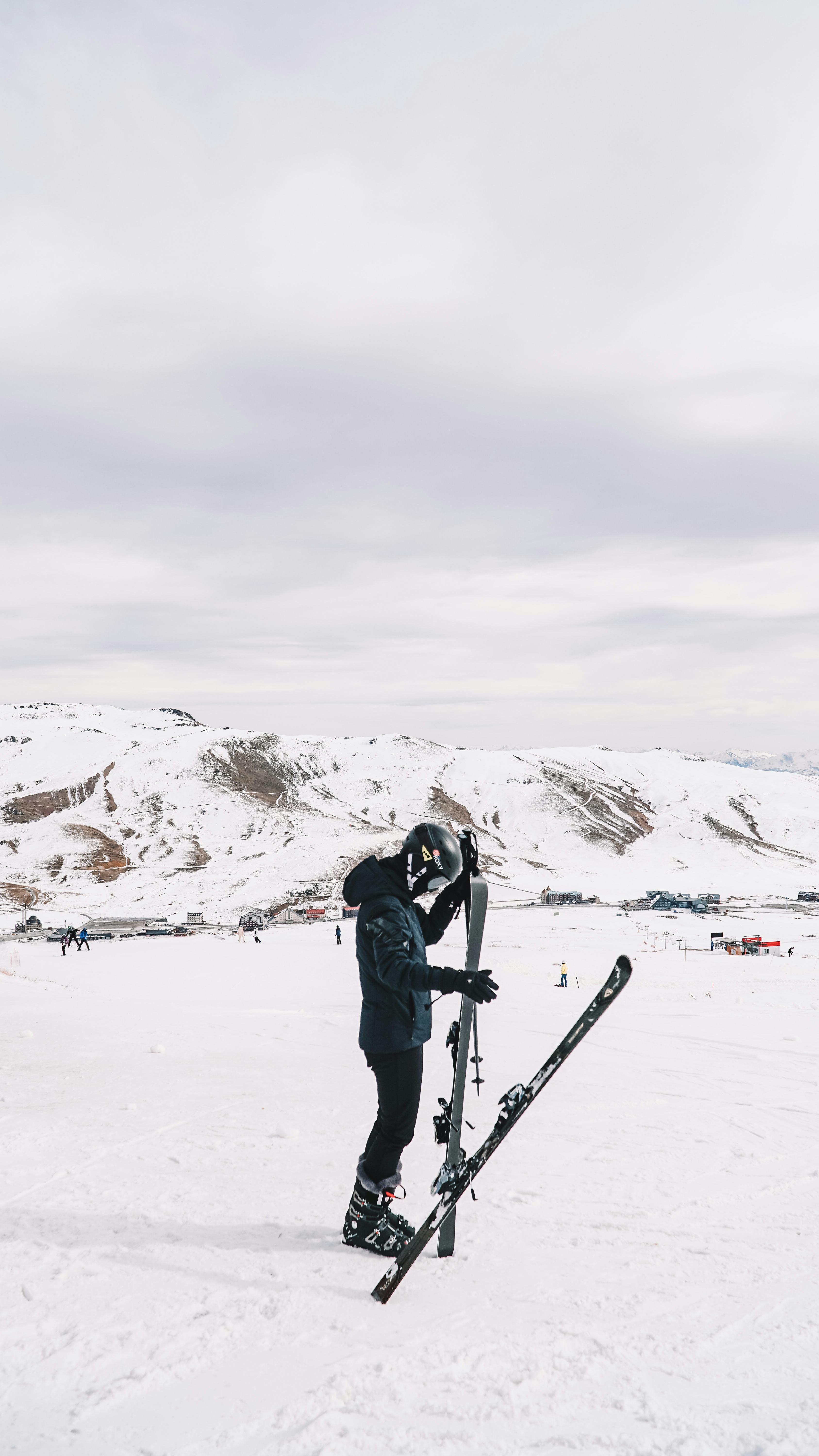 Prescription Goggle Inserts - Skier adjusting gear in snowy mountains, showcasing winter sports leisure.