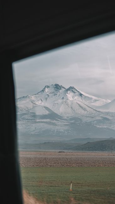 Scenic view of snowy mountain landscape through a car window, capturing winter's beauty.