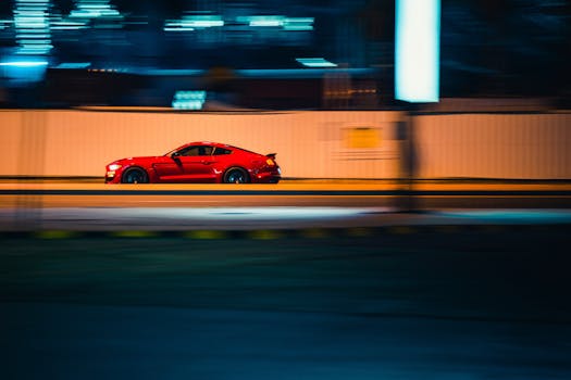 A vibrant red sports car speeding through Kuwait City at night, showcasing motion and speed.