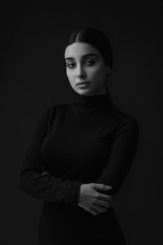Black and white portrait of a young woman posing elegantly in a studio setting.
