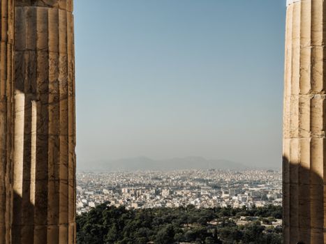 Explore Athens cityscape through historical columns, highlighting the blend of ancient and urban Greece.