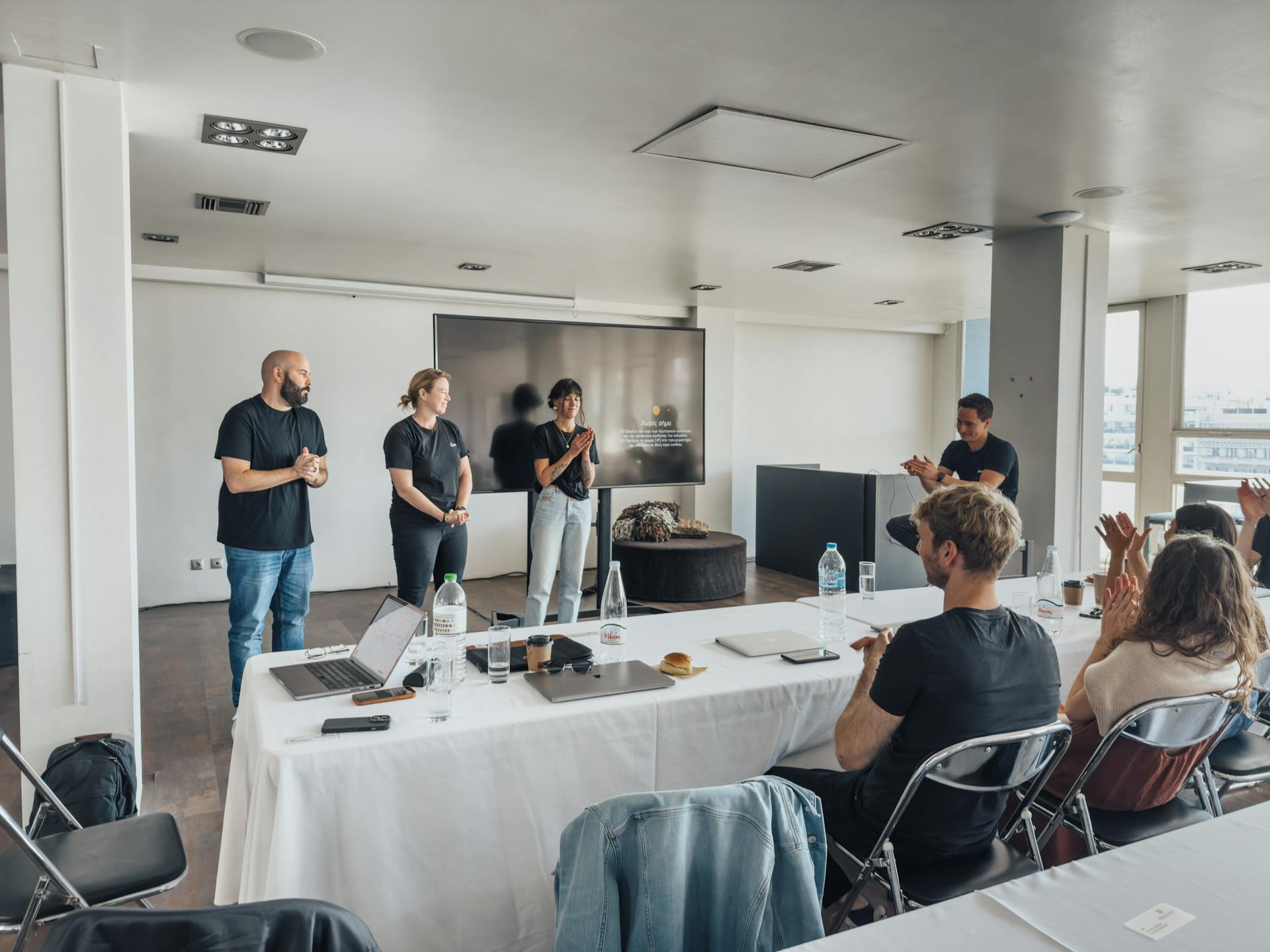 Team presenting ideas in a modern office with attentive audience and tech equipment.