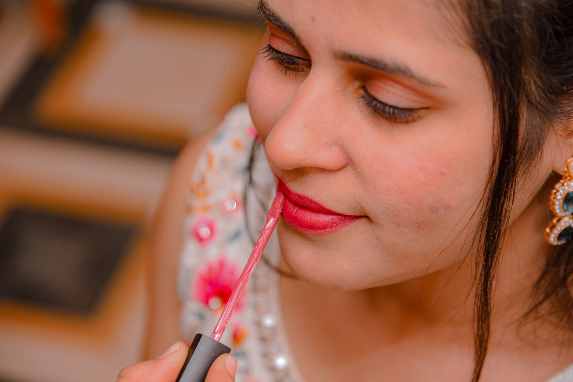 A woman applying bright lipstick with focus on makeup details.