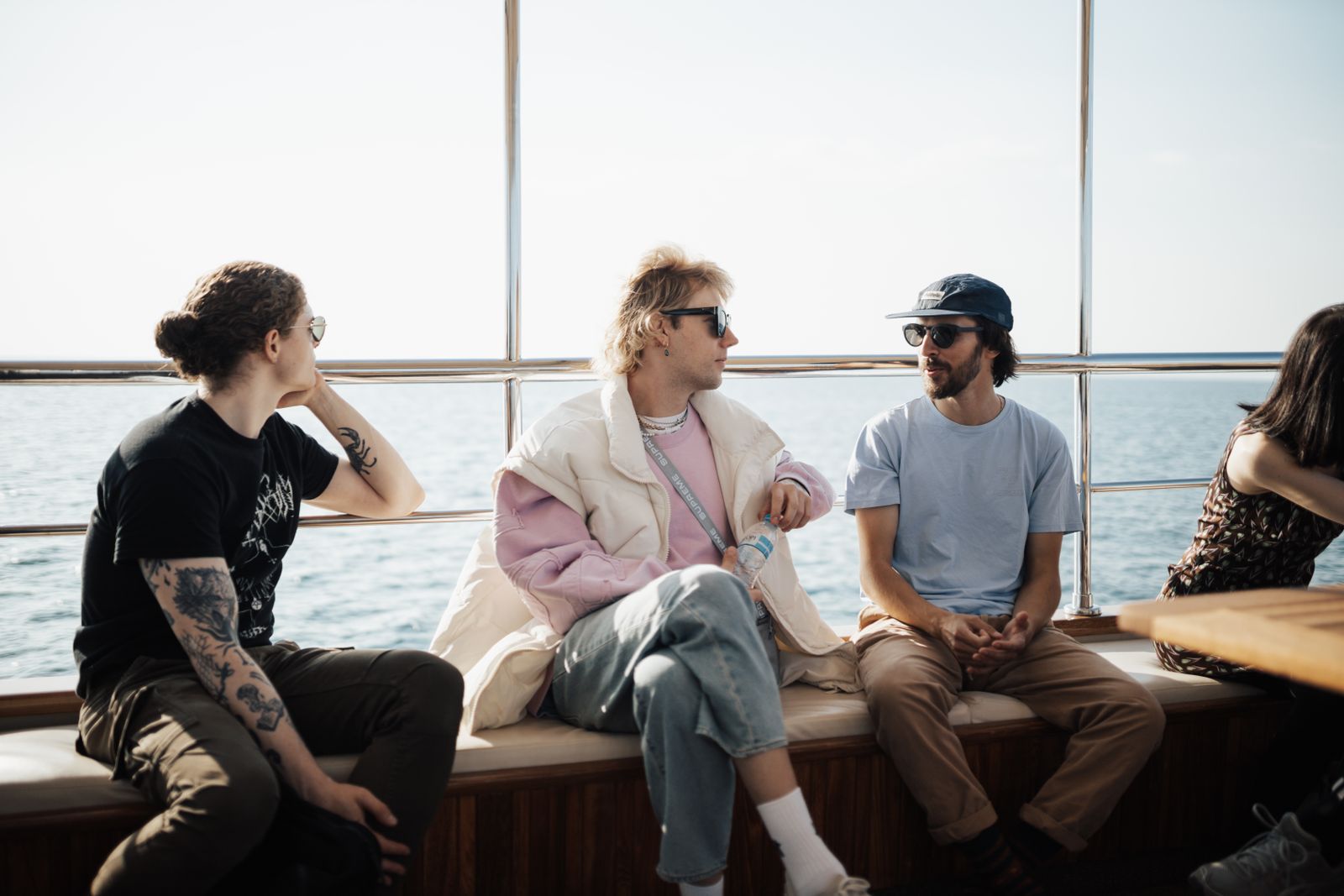A group of friends in relaxed conversation on a yacht deck with an ocean view