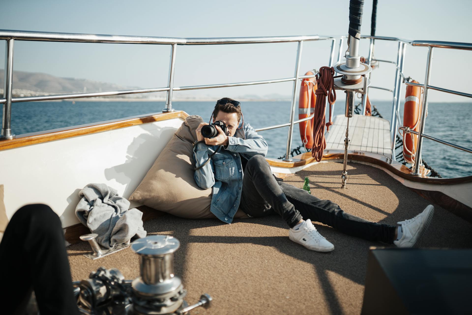 Young man on yacht photographing ocean, relaxed setting