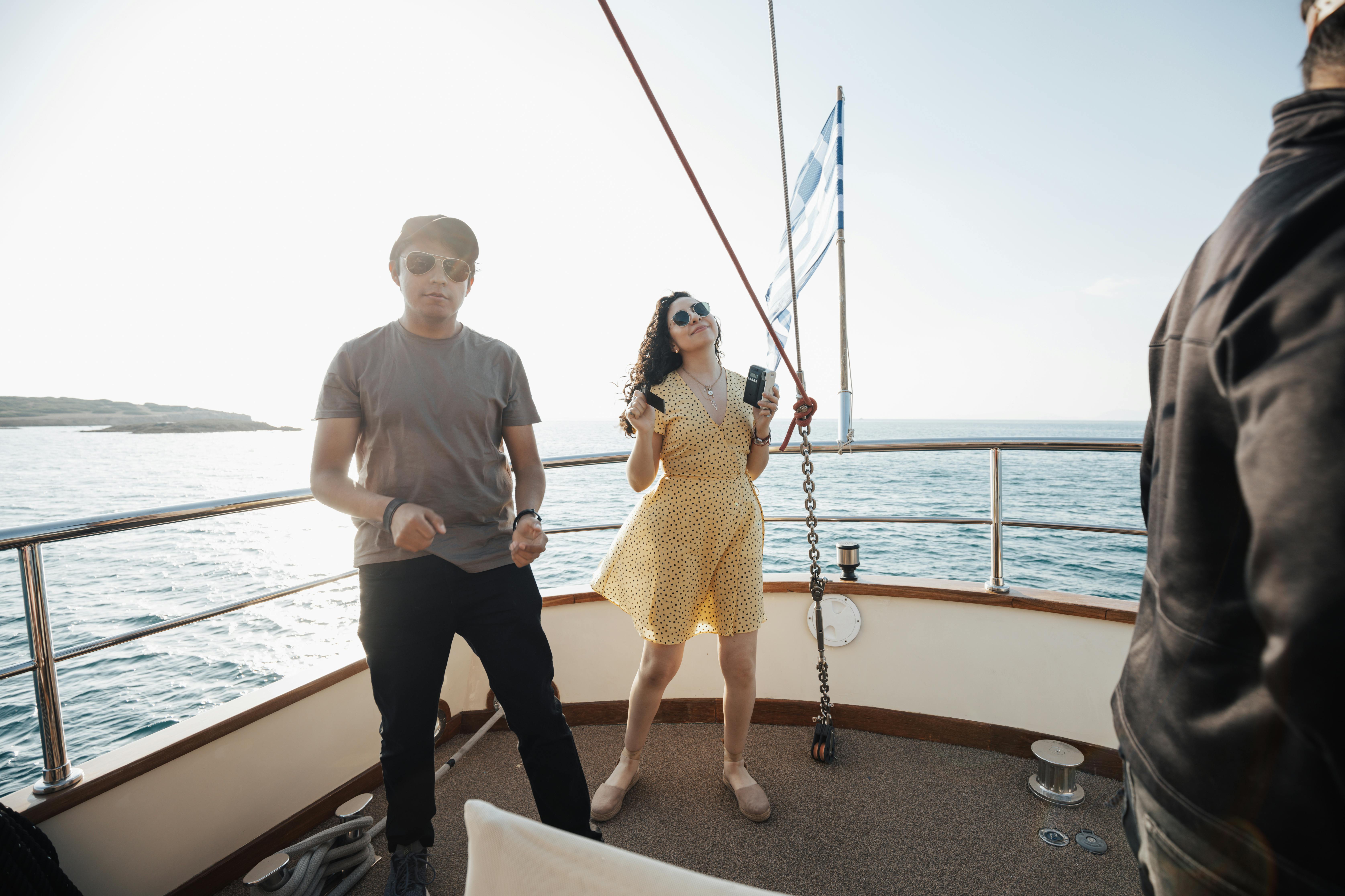 Young adults having fun on a yacht under sunny skies, enjoying leisure time on the sea.