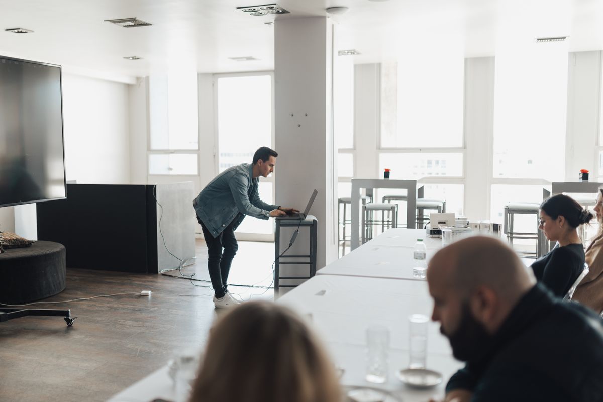 A man presenting slides to a group of colleagues in a bright meeting room