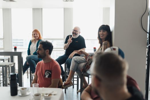 A group engaging in a relaxed, cheerful office meeting with laughter and dialogue.