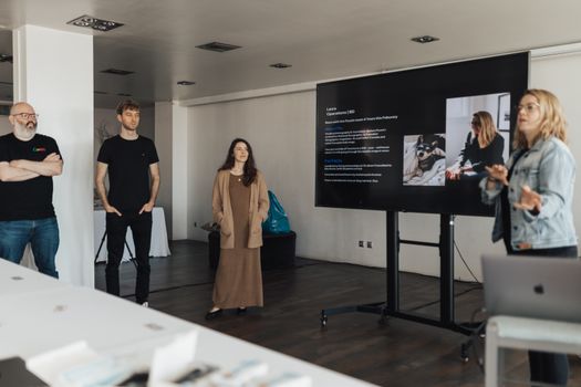 Team gathers around a digital presentation in a modern office setting.