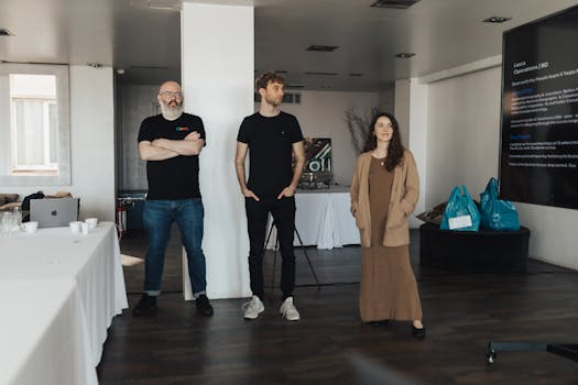 Three professionals presenting in a modern office with large screen display.