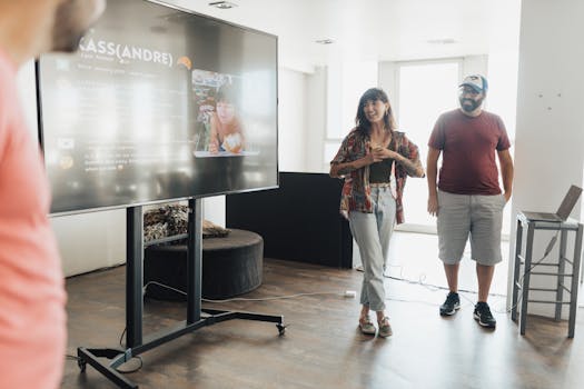 A casual business presentation with team members gathered around a screen discussing ideas.