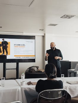 A business professional delivers a presentation to colleagues in a modern meeting room setting.