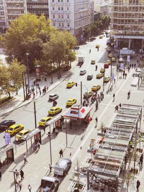 Free Aerial view of a busy street in Athens showing yellow taxis, pedestrians, and urban landscape. Stock Photo