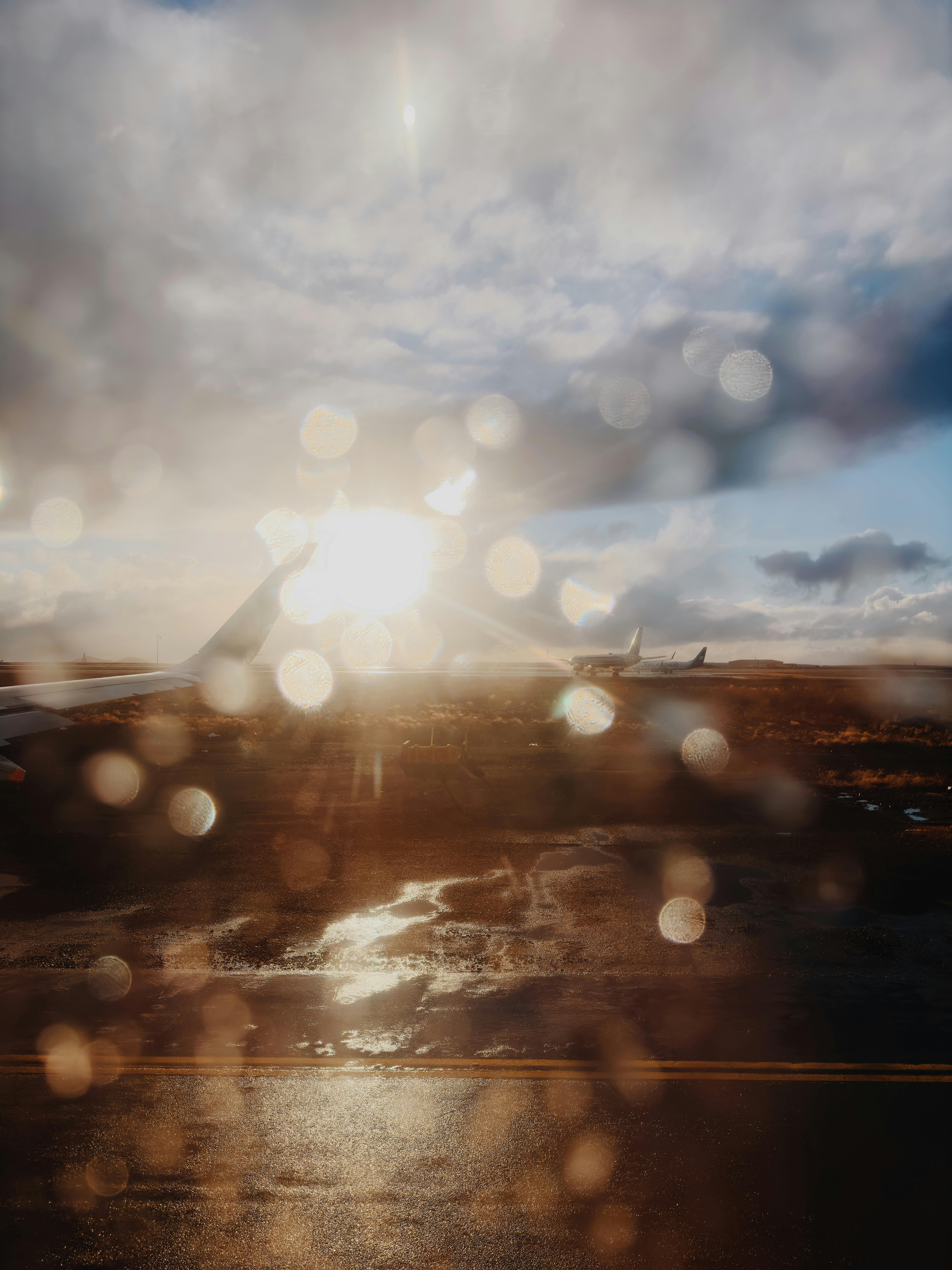 View from an aeroplane window over the tarmac of an Icelandic airport at sunset in the rain