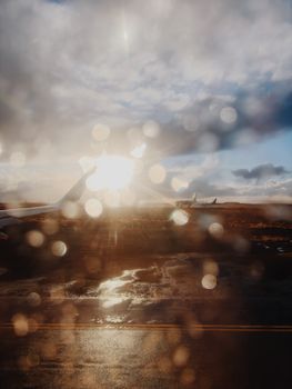 A stunning view of an airport tarmac at sunset through a raindrop-covered window in Iceland.