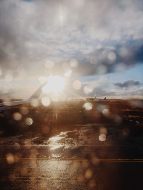 View from an aeroplane window over the tarmac of an Icelandic airport at sunset in the rain