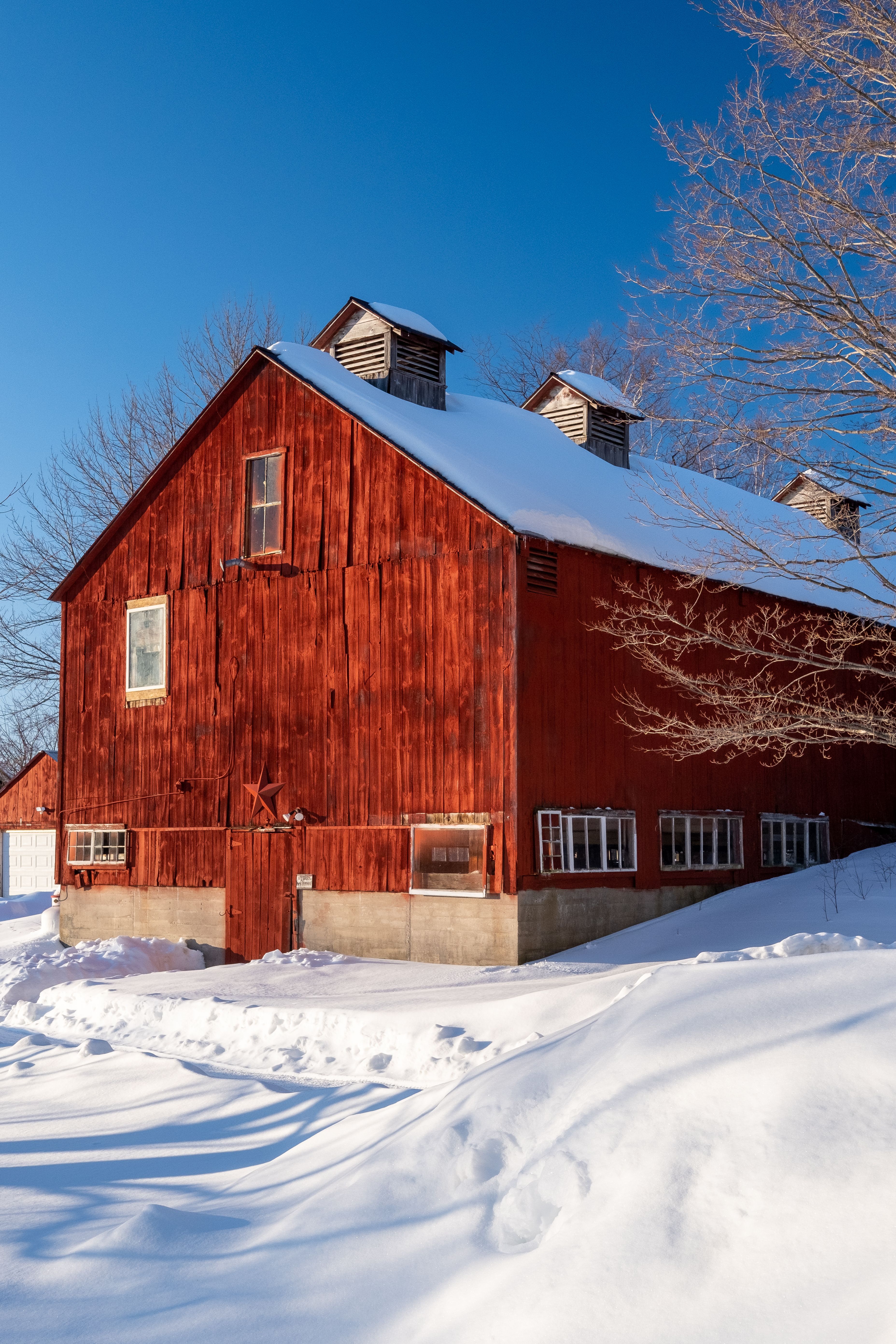 A red barn in the snow with a blue sky · Free Stock Photo