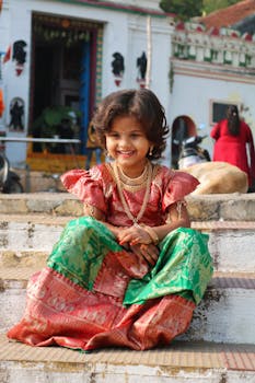 Happy child in vibrant Indian traditional dress, smiling outdoors.