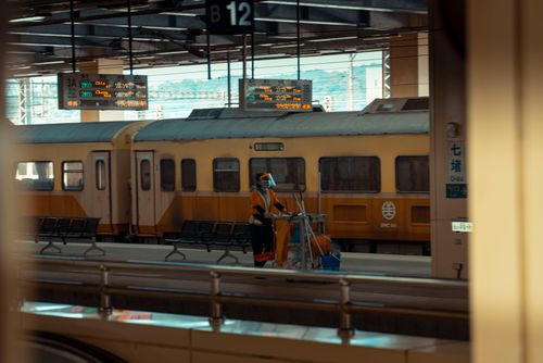 Free A railway station cleaner at work beside a train on the platform, depicting urban transportation. Stock Photo