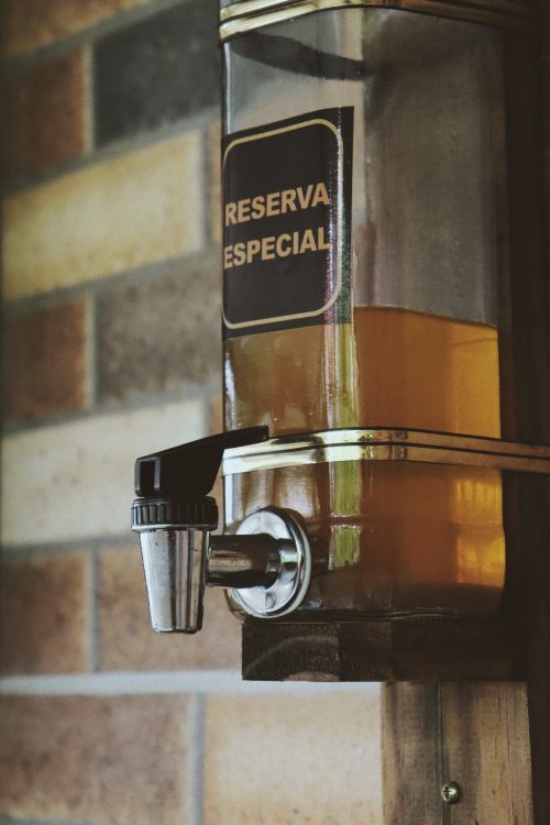 Free A vertical shot of a Reserva Especial drink dispenser with a tap against a brick wall. Stock Photo