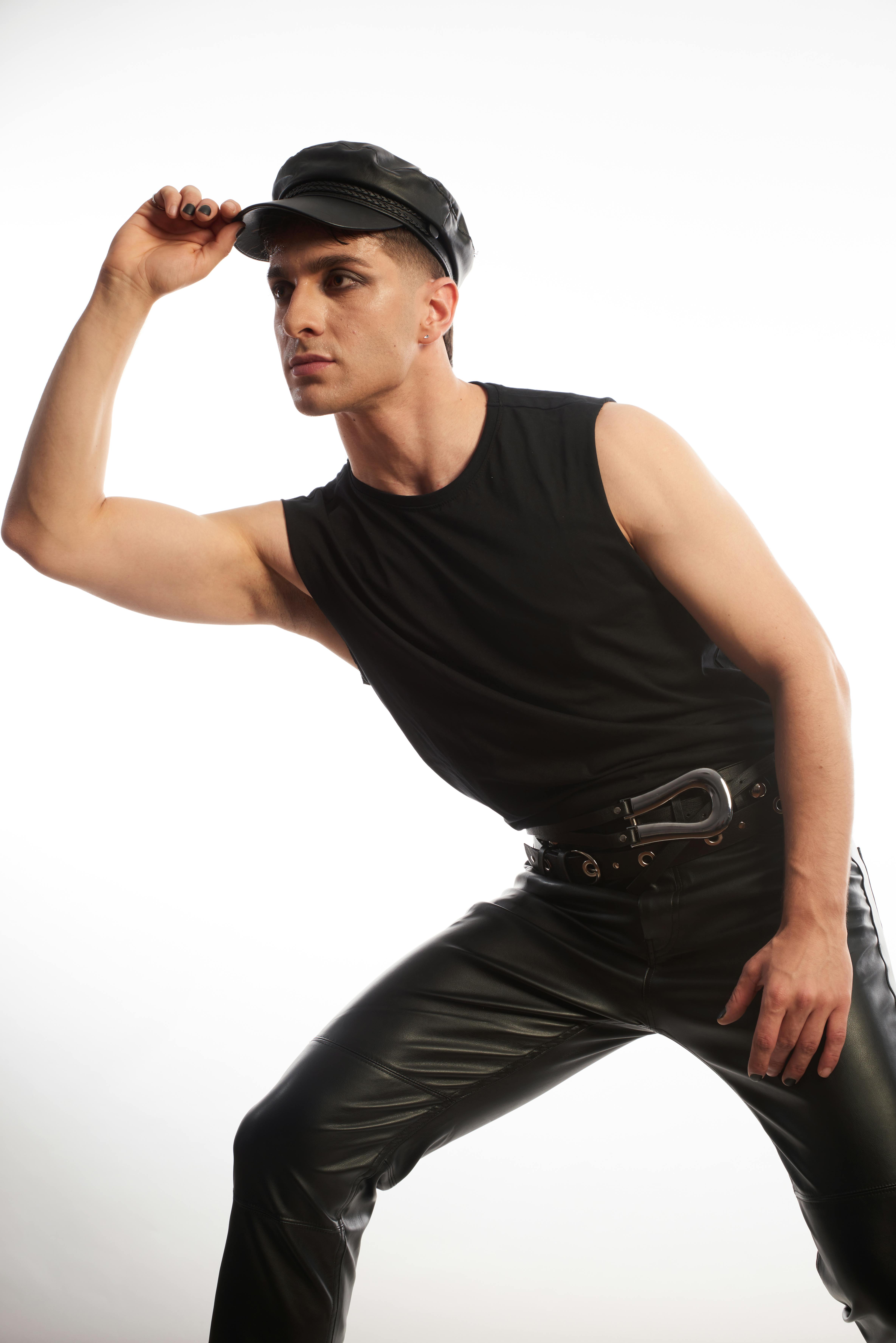 Man in a stylish black outfit posing against a white background.