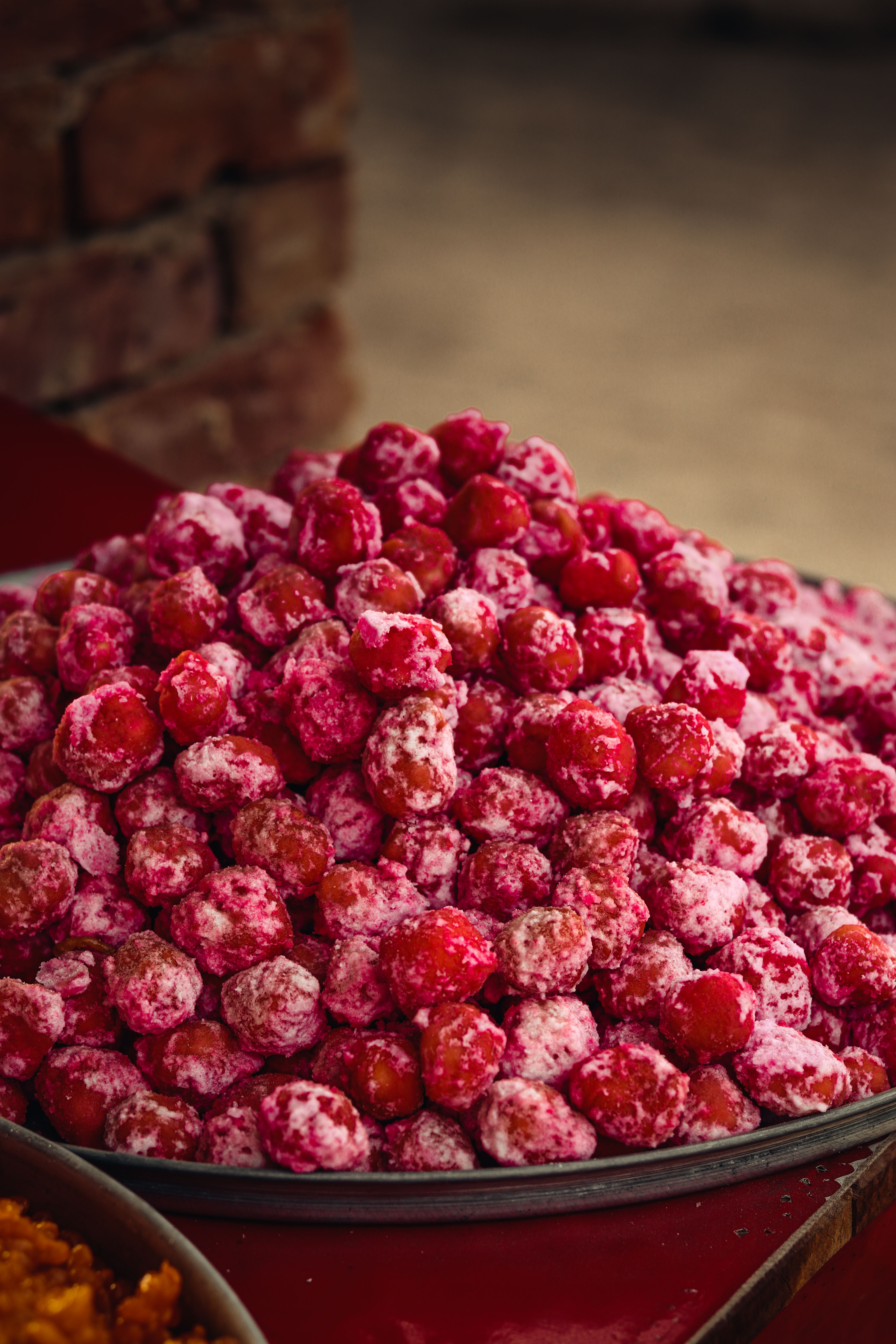 Close-up of a piled tray of sugar-coated red berries at an outdoor market display.