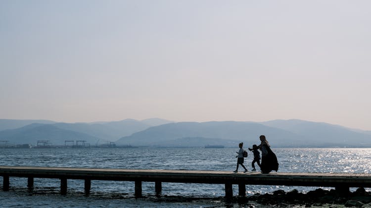 A Silhouette Of A Family Walking On A Pier