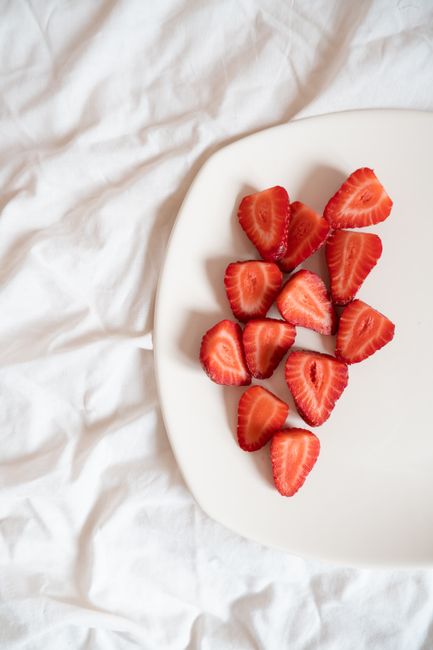 Top view of sliced strawberries on a plate over white bedsheet. Healthy eating concept.