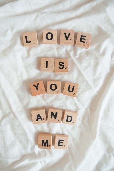 Love message formed with wooden letter tiles on a soft white background.