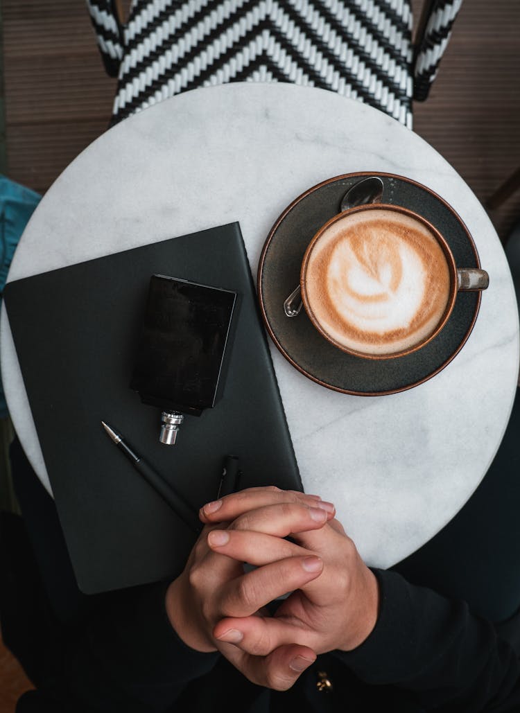 Man Sitting At The Table With A Coffee And Notebook 