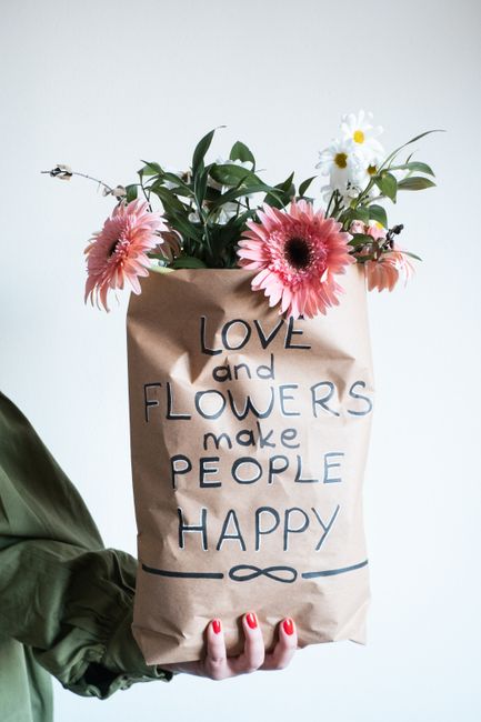 A bouquet of flowers in a paper bag with the quote 'Love and Flowers make People Happy'
