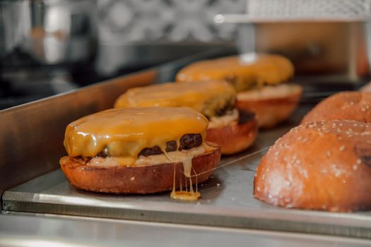 Close-up of sizzling cheeseburgers with melted cheddar cheese, perfect for fast food lovers.
