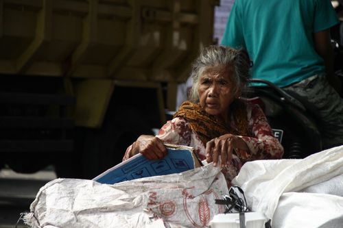 Free Elderly woman sitting among bags outdoors during the day, reflecting on life. Stock Photo
