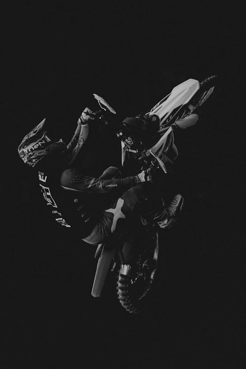 Grayscale Photo of Man Riding a Motocross Bike