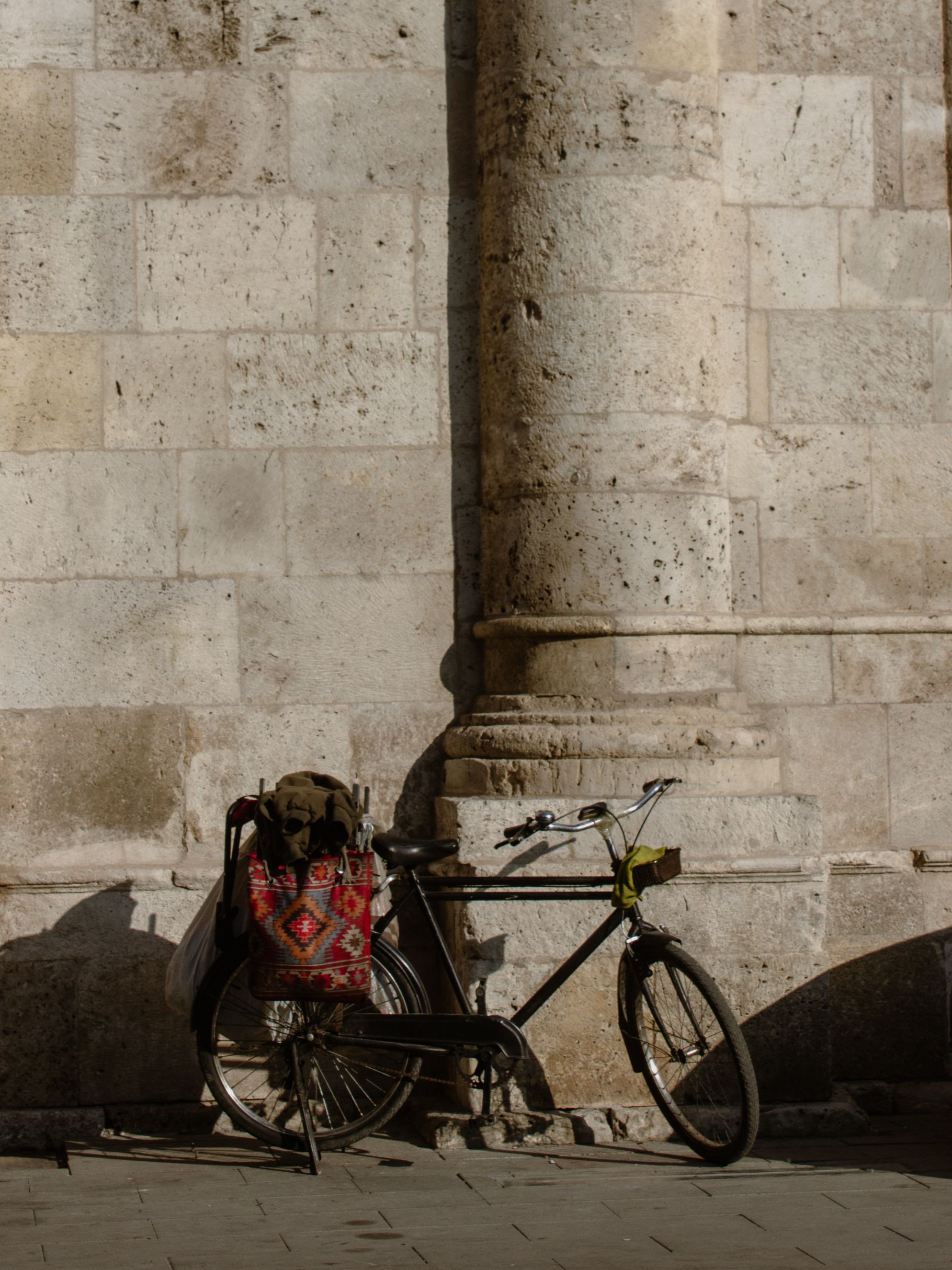 A vintage bicycle parked against a historic stone wall in Konya, Türkiye, during daylight.