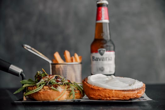 Close-up of a gourmet burger with fries and beer on a gray background, perfect for food and lifestyle imagery.