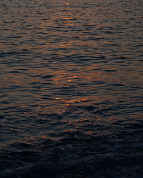 Free Ocean waves reflecting vibrant sunset colors, creating a tranquil and picturesque scene. Perfect for relaxation themes. Stock Photo
