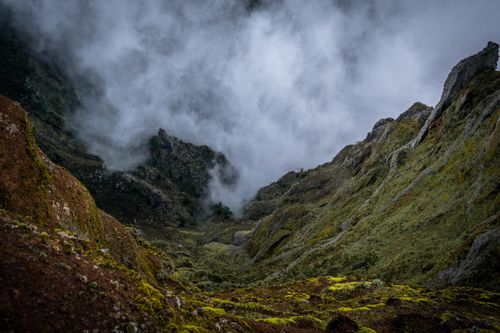 Free A breathtaking view of rugged mountains enveloped in fog, creating a dramatic and mystical atmosphere. Stock Photo