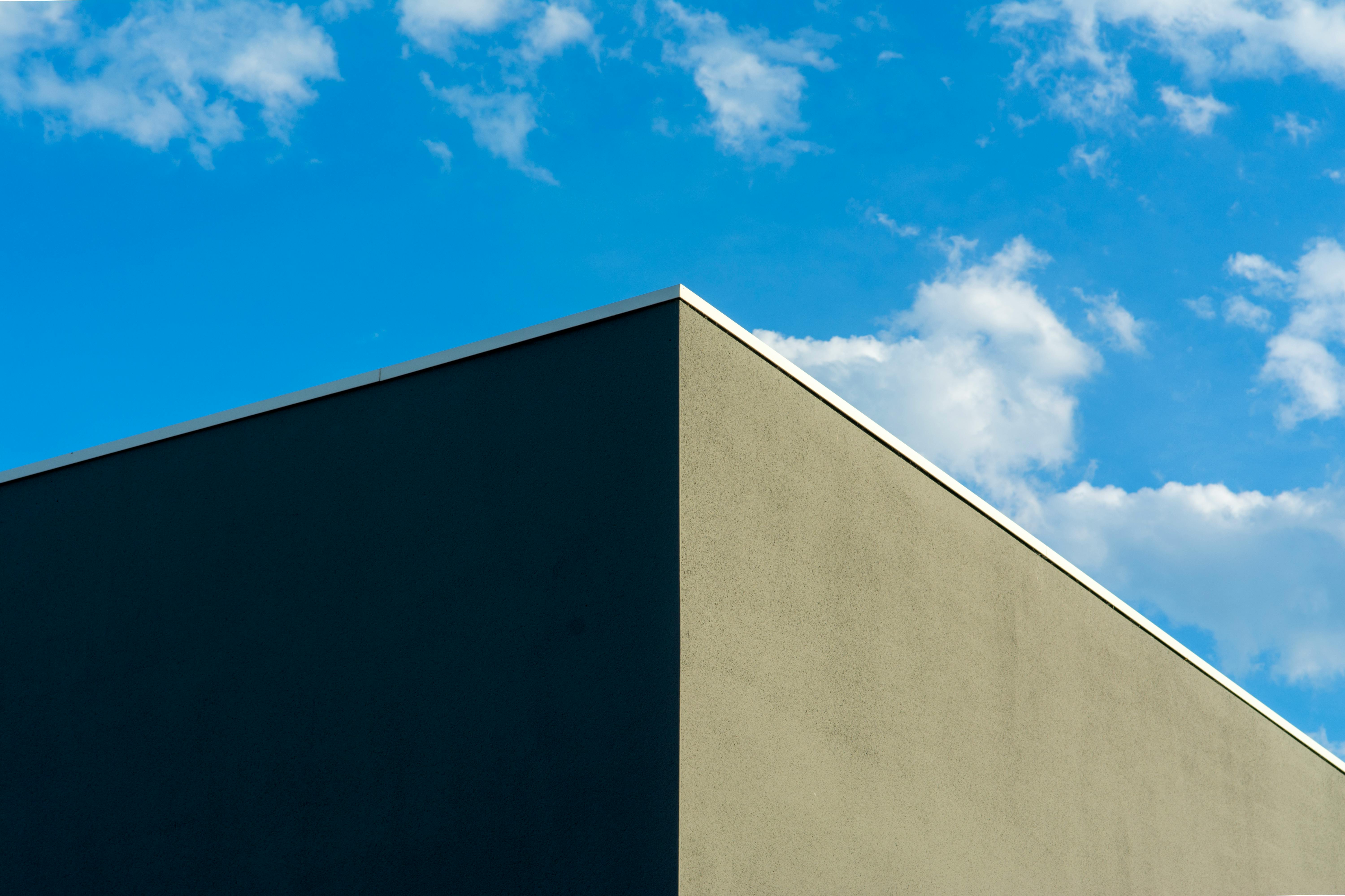 Free Minimalist building corner against a vibrant blue sky with clouds. Stock Photo