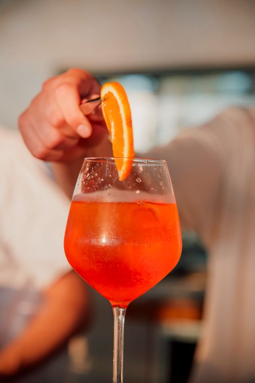 Free Close-up of an Aperol Spritz cocktail with a fresh orange slice garnish outdoors. Stock Photo