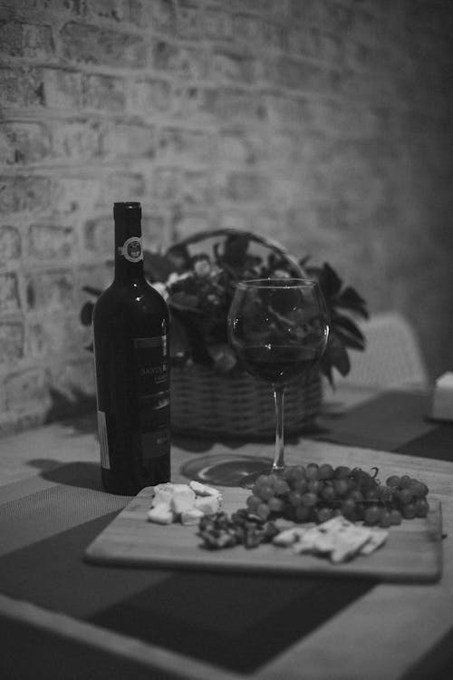 Glass and Bottle of Wine and Grapes on Tray on Table