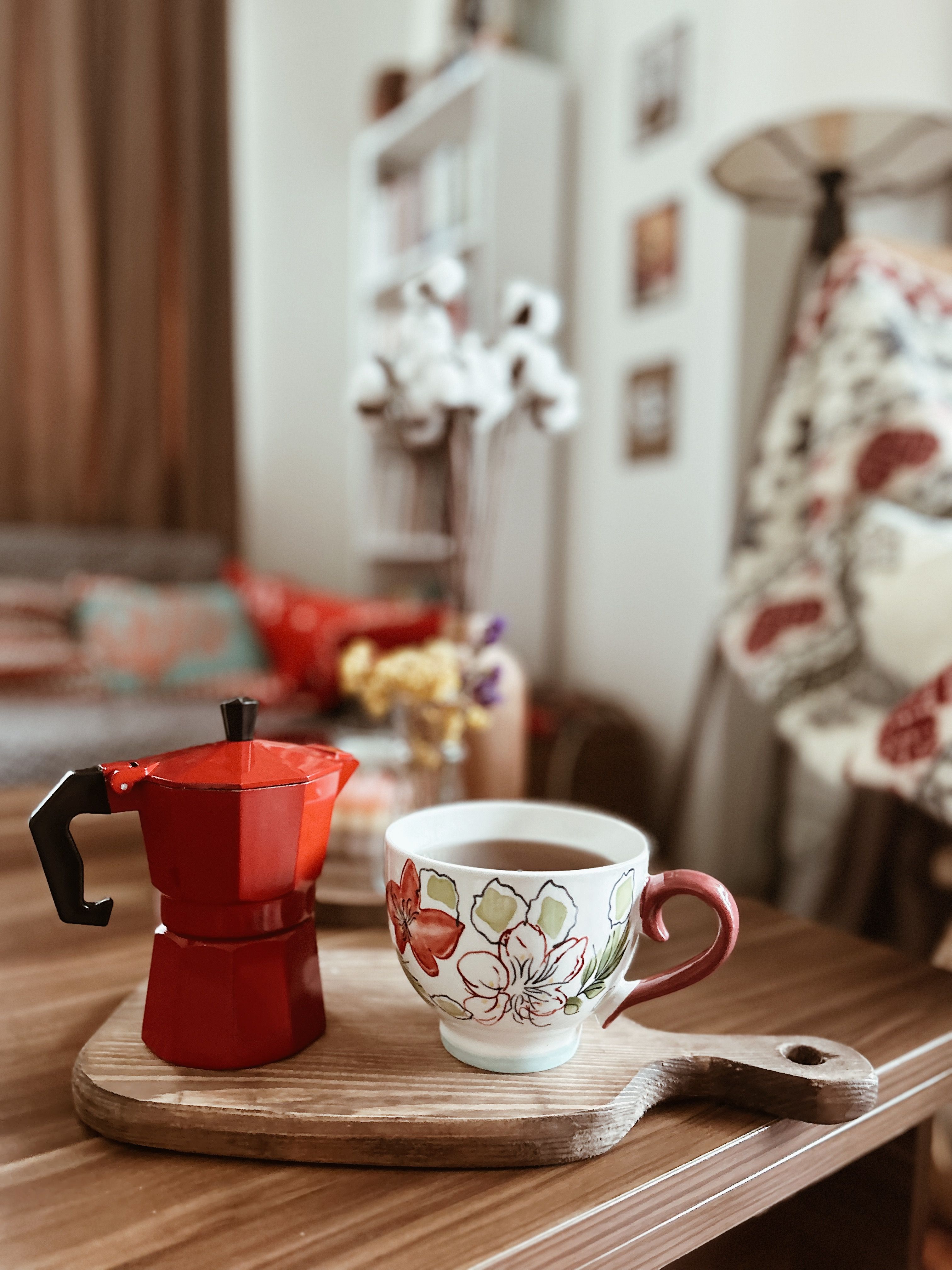 A warm cup of coffee and pot on a wooden tray in a cozy Turkish living room.