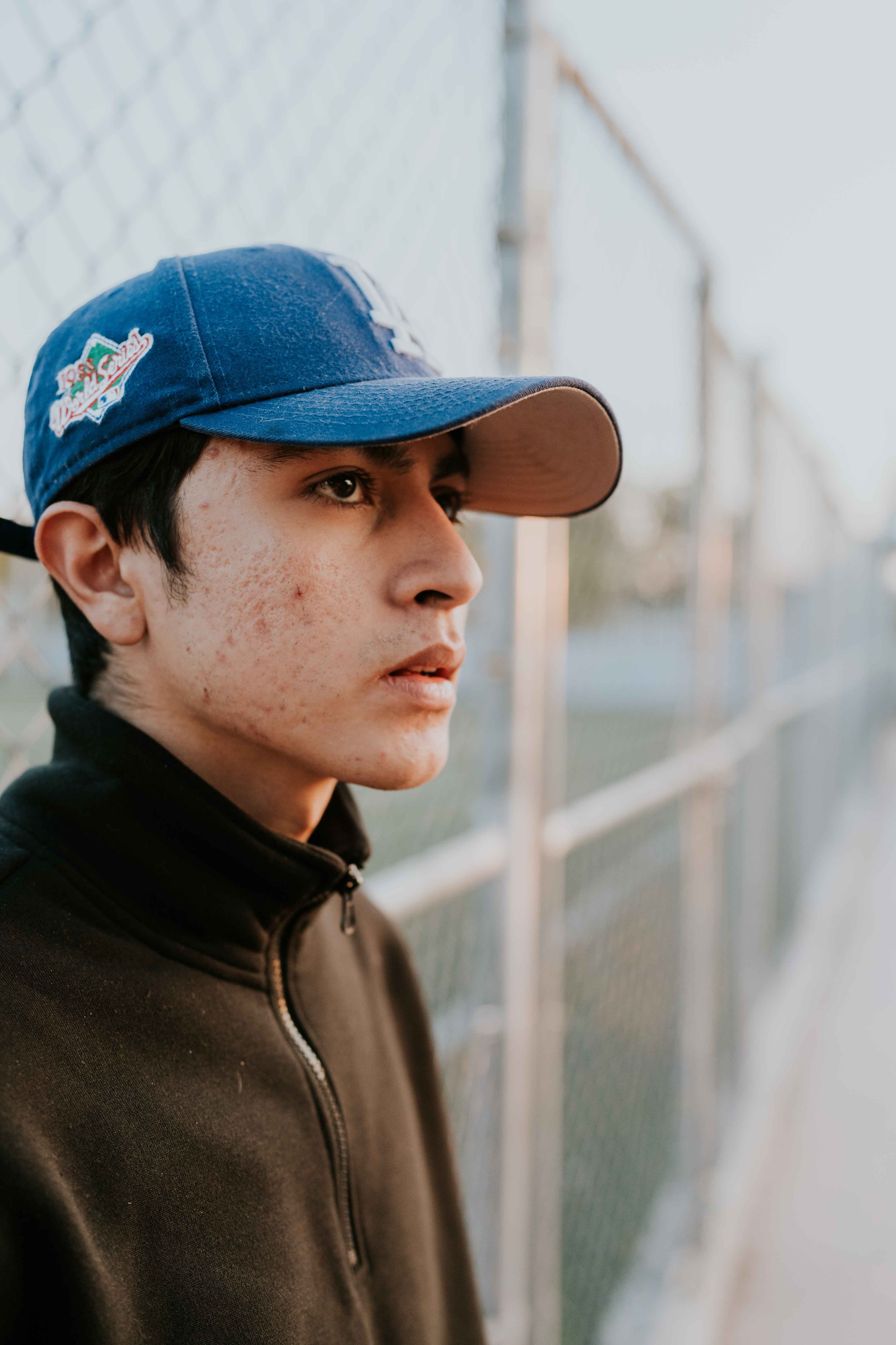 Boy in Cap by Fence · Free Stock Photo