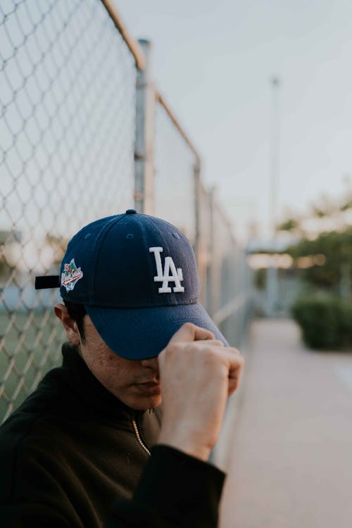 Man Holding Visor of Blue Baseball Cap